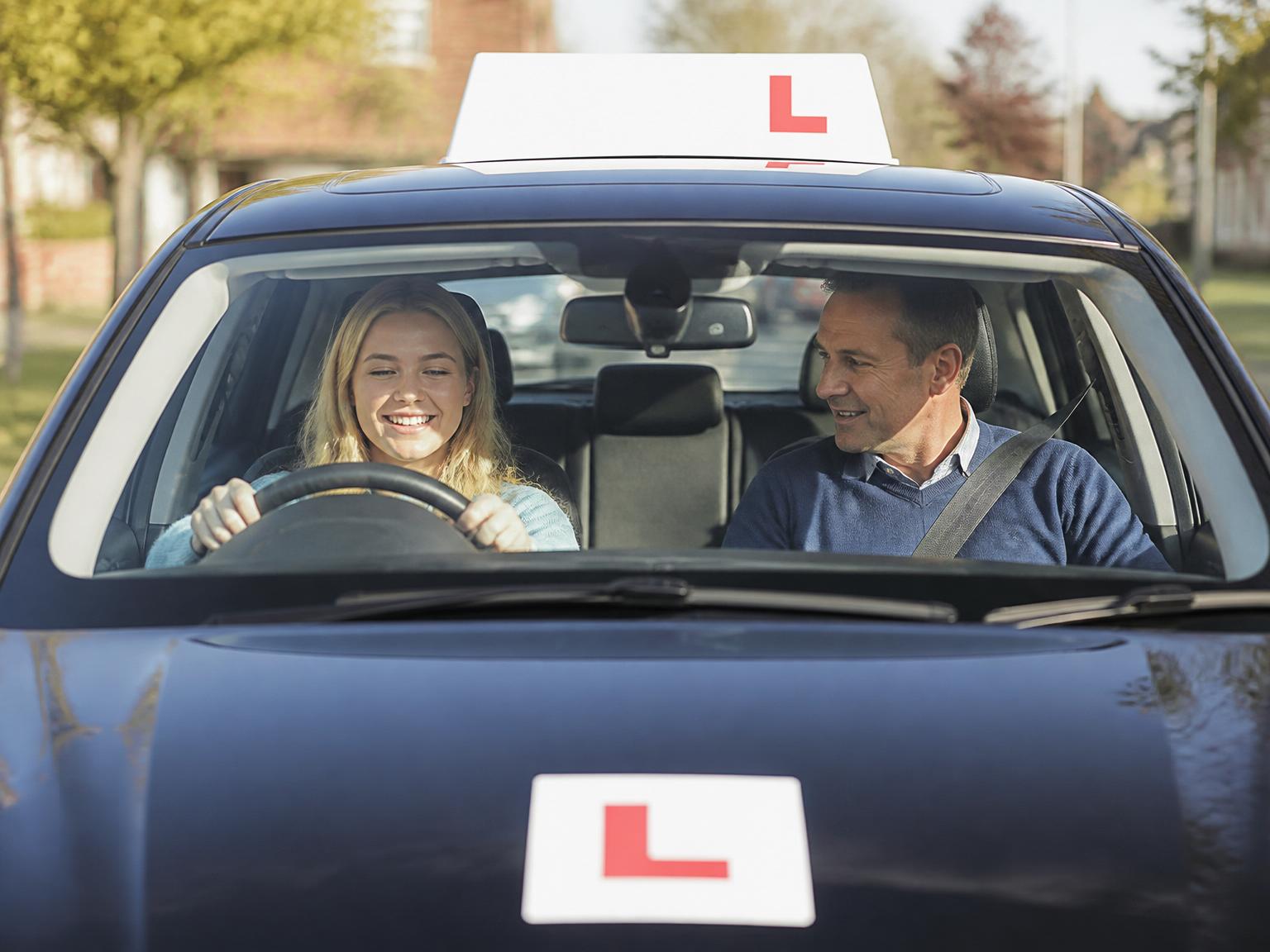 Learner driver smiling with instructor during a driving lesson